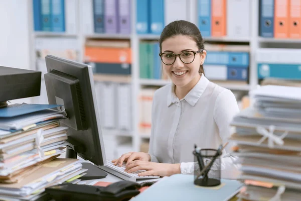 Joven Secretaria Sonriente Trabajando Escritorio Oficina Montones Papeleo — Foto de Stock