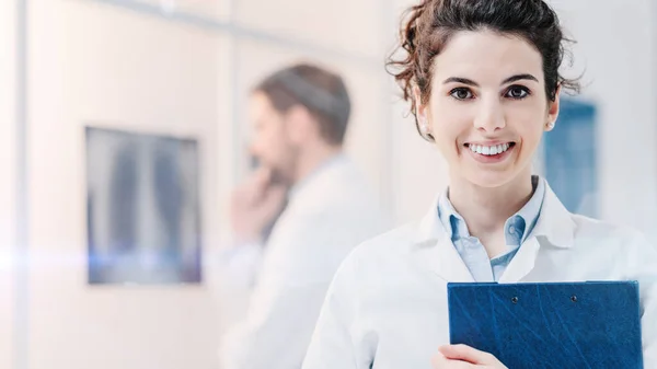 Joven Doctora Sonriendo Sosteniendo Portapapeles Doctor Está Examinando Una Radiografía — Foto de Stock