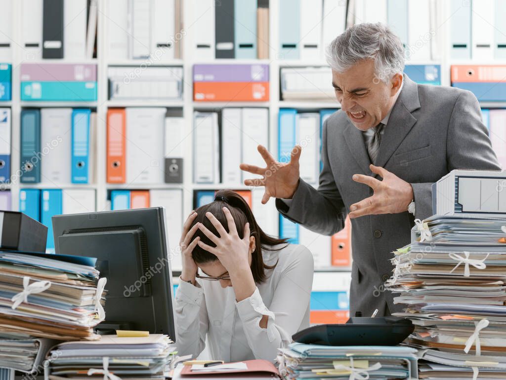 Angry boss yelling at his young employee, she is stressed and feeling frustrated: hostile boss and mobbing concept