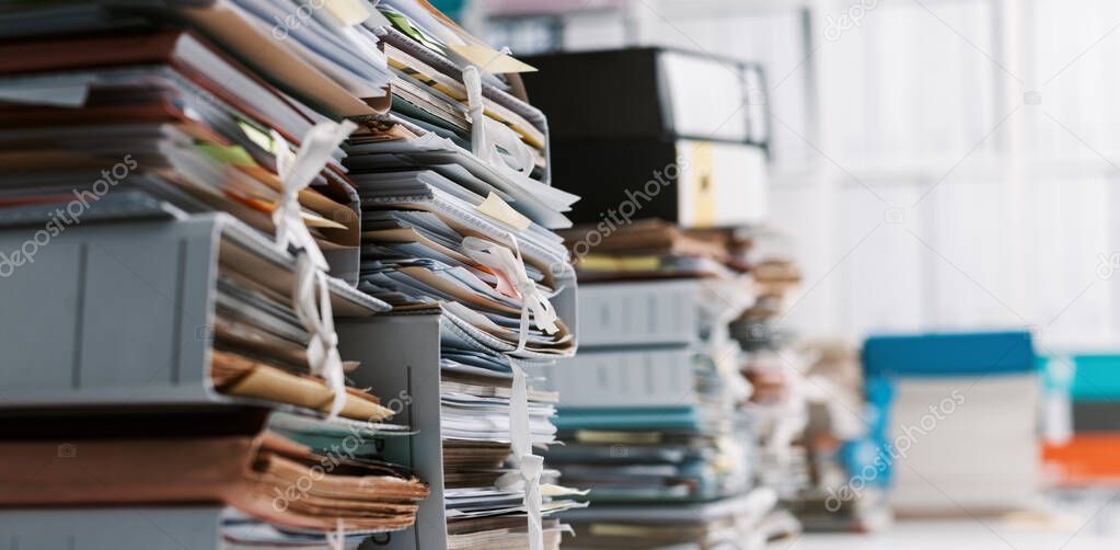 Stacks of paperwork and files in the office: work overload, files management and administration concept