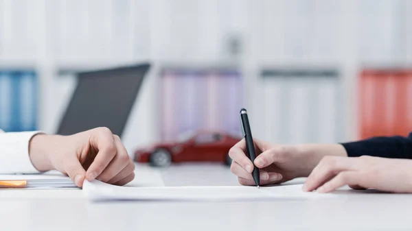 Женщина Подписывает Автостраховку Офисе Модель Автомобиля Заднем Плане — стоковое фото