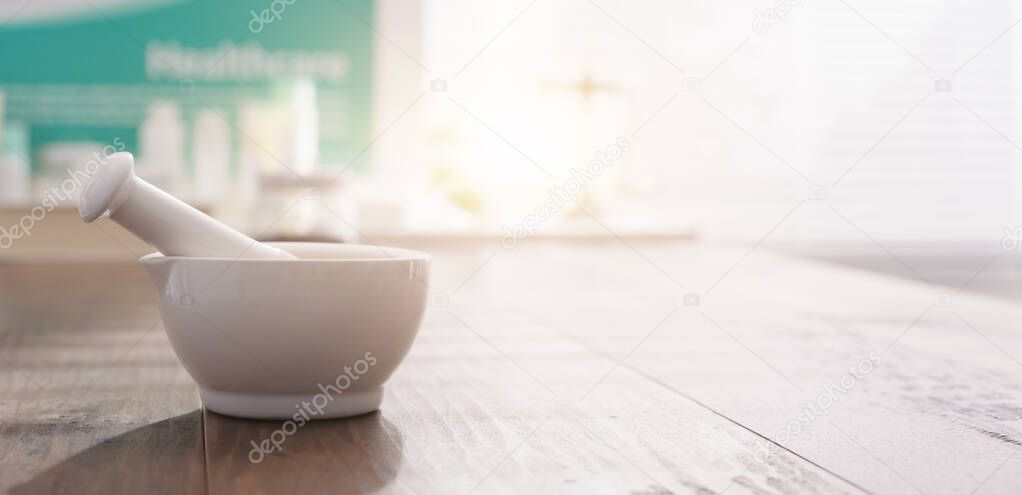 Mortar and pestle on the pharmacist's table and pharmaceutical products on the background