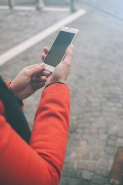 Sokakta tanınmayan bir kadın cep telefonunu kullanıyor, elleri kapalı.