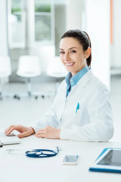 Médico Femenino Trabajando Escritorio Oficina Sonriendo Cámara Ella Está Usando —  Fotos de Stock