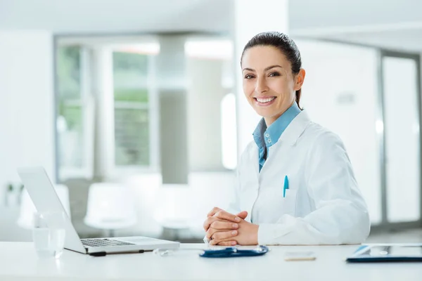 Ärztin Schreibtisch Und Lächelnd Die Kamera Büroeinrichtung Hintergrund — Stockfoto