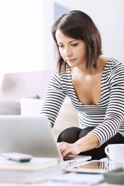 女人在家里放松 她坐在沙发上 使用笔记本电脑 与互联网相连 — 图库照片