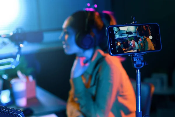 年轻女子用她的智能手机在直播视频中播放 并在演播室里对着话筒说话 — 图库照片