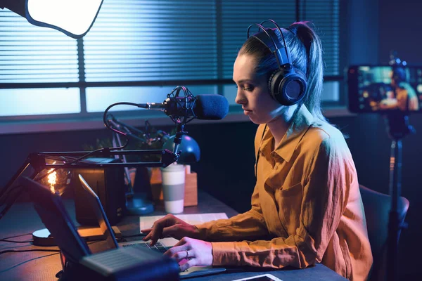 Young woman streaming a live video with her smartphone and talking into a microphone