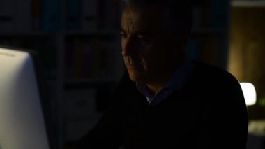 Gece geç saatlerde bilgisayar sorunları yaşayan bir adam.