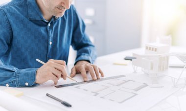 Ofis masasında çalışan profesyonel mimar, bir proje planı, tasarım ve mimari konsepti üzerine ölçümler çiziyor ve yapıyor.