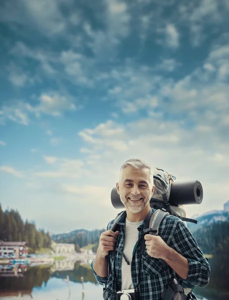 山の上で成熟したハイカーのトレッキングや自然を探索し 彼はカメラ スポーツ 健康的なライフスタイルのコンセプトで笑っています — ストック写真
