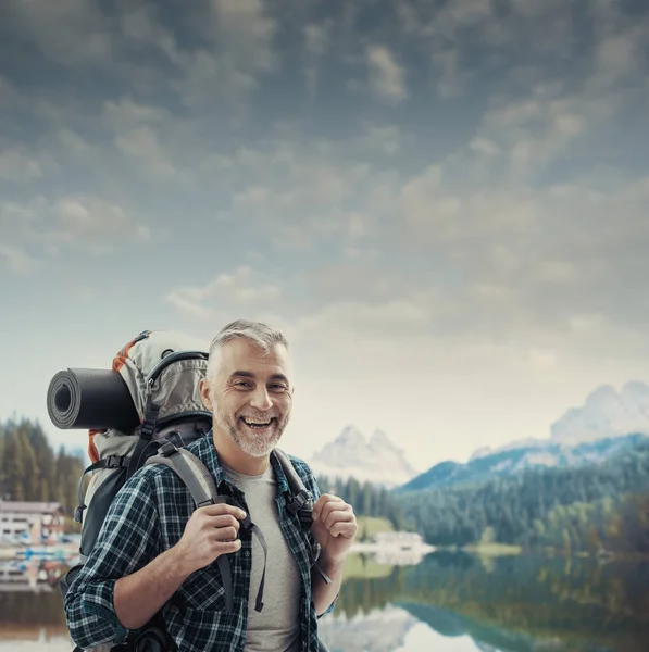 自信を持って成熟したハイカーのトレッキングや山の自然を探索し 彼はカメラでバックパックと笑顔を運んでいます — ストック写真