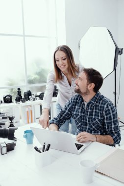 Yaratıcı ajansta çalışan fotoğrafçı ve tasarımcı bir dizüstü bilgisayarla bağlantı kuruyor.