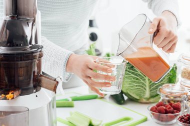 Kadın bardağa taze ev yapımı meyve suyu dolduruyor. Sağlıklı yemek ve spor konsepti.