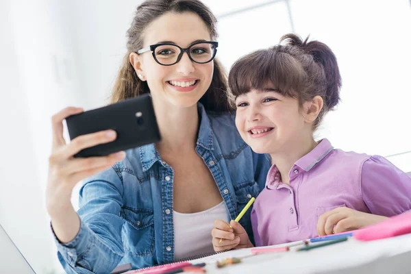 可爱的女孩和她的年轻妈妈在家里拿着智能手机自言自语 他们面带微笑 玩得很开心 — 图库照片