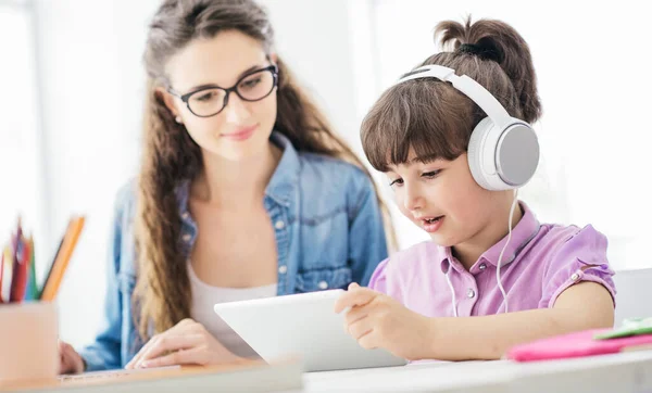 年轻的妈妈和女儿一起在家里用数字平板电脑观看视频 女孩戴着耳机 — 图库照片