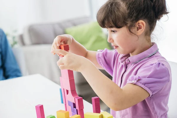 Cute girl playing with toy wood blocks at home, learning and playing concept
