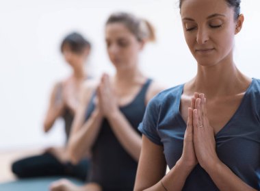 Yoga ve farkındalık meditasyonu yapan kadınlar el ele tutuşup rahatlatıcı, sağlıklı yaşam tarzı ve maneviyat kavramını benimsiyorlar.