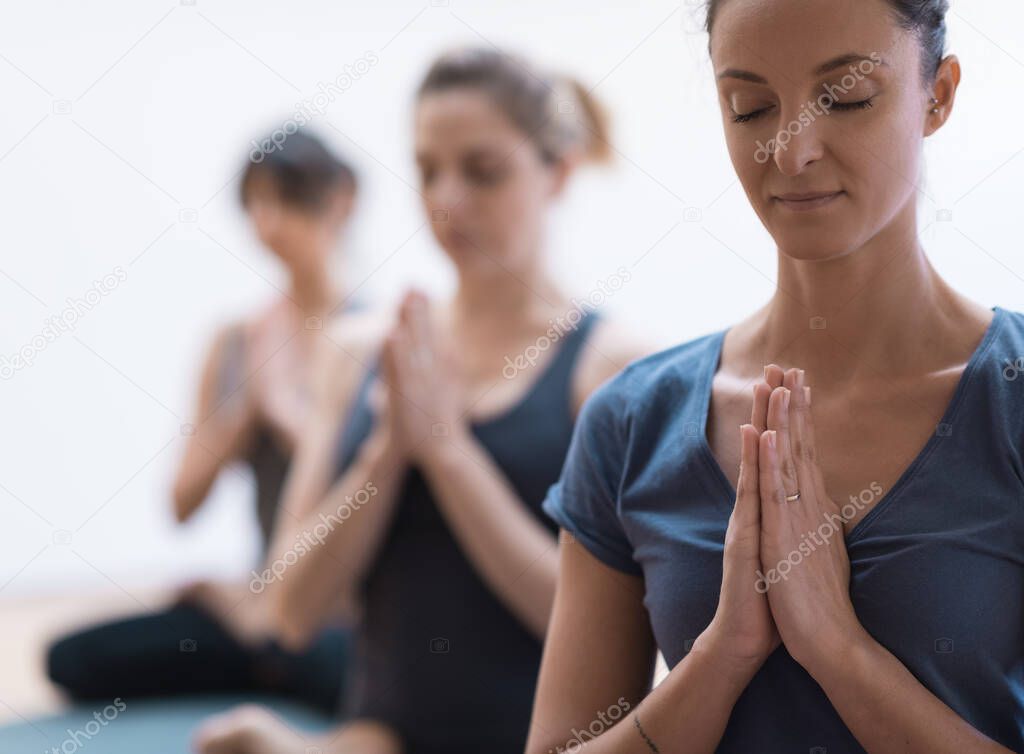 Women practicing yoga and mindfulness meditation together, they are clasping hands and relaxing, healthy lifestyle and spirituality concept