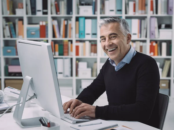 Hombre Negocios Seguro Sentado Escritorio Trabajando Con Computadora Está Sonriendo — Foto de Stock