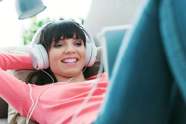 Smilende Ung Kvinde Slapper Hjemme Sofaen Hun Har Hovedtelefoner Bruger - Stock-foto