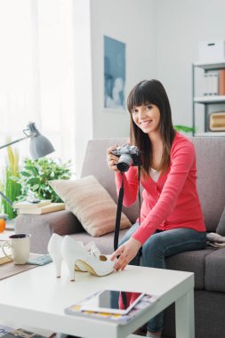 Genç, gülümseyen bir kadın, elinde kamerayla ayakkabılarını çekiyor. Onları bir internet mağazasında satacak. 