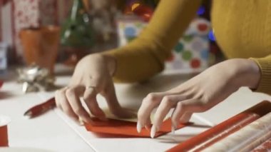 Bir kadın zarfa Noel kartı koyuyor.