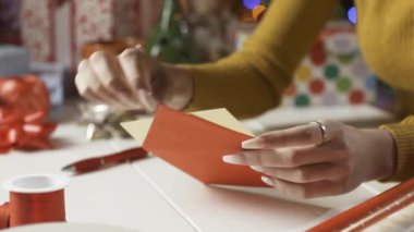 Bir kadın zarfa Noel kartı koyuyor.
