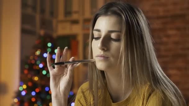 Улыбающаяся женщина пишет рождественскую открытку с пожеланиями — стоковое видео