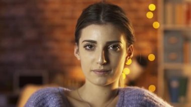 Güzel kız evde poz veriyor ve kameraya gülümsüyor.