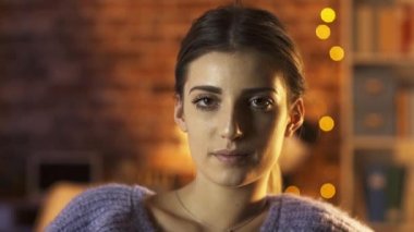 Güzel kız evde poz veriyor ve kameraya gülümsüyor.