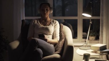 Kız gece evde dinleniyor ve müzik dinliyor.