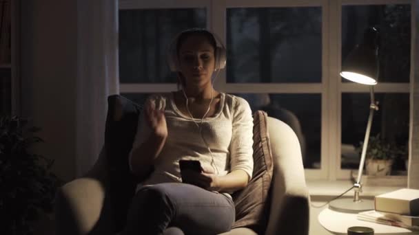 Girl relaxing at home at night and listening to music — Stock Video