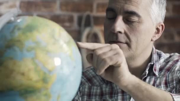 Happy man searching random places on a globe — Stock Video