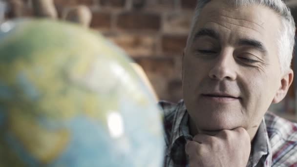 Happy man searching random places on a globe — Stock Video