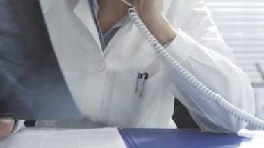 Gülümseyen doktor röntgen çektiriyor ve telefon görüşmesi yapıyor.