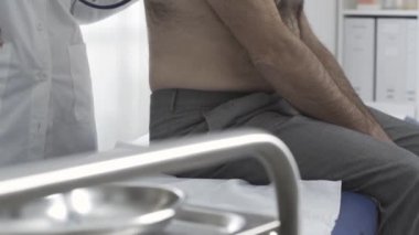 Doktor steteskoplu bir hastayı dikkatlice inceliyor.