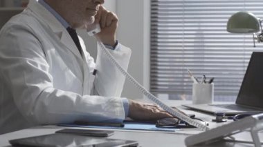 Kıdemli doktor telefonda danışmanlık yapıyor.