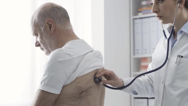 Médico examinando cuidadosamente um paciente com um estetoscópio — Vídeo de Stock