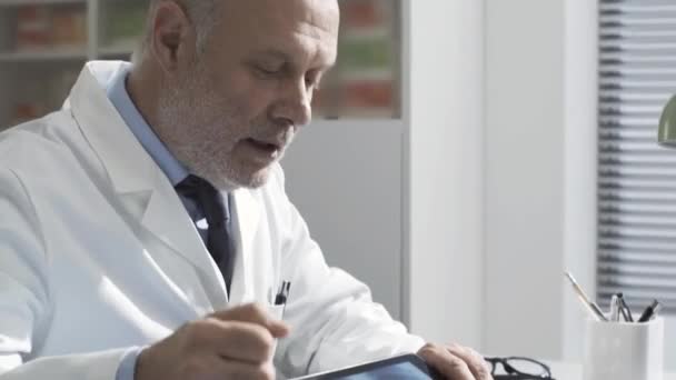 Ο γιατρός δείχνει μια ακτινογραφία σε έναν ασθενή χρησιμοποιώντας ένα δισκίο — Αρχείο Βίντεο