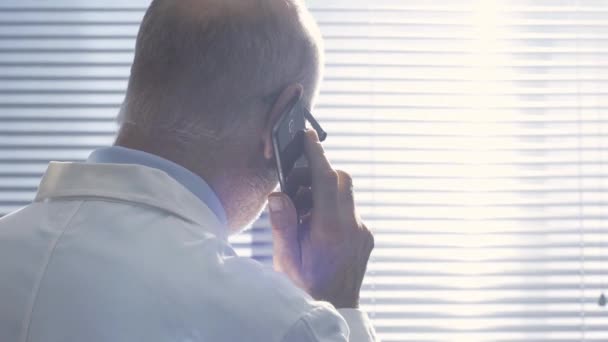 Médico que dá uma consulta a um paciente ao telefone — Vídeo de Stock