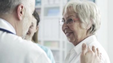 Klinikteki sağlık personeliyle konuşan kıdemli bir kadın.
