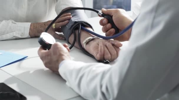 Médico que mede a pressão arterial de um paciente idoso — Vídeo de Stock