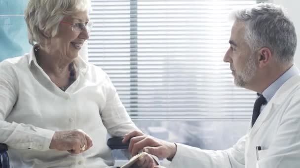 Médecin professionnel réconfortant un patient âgé en fauteuil roulant — Video