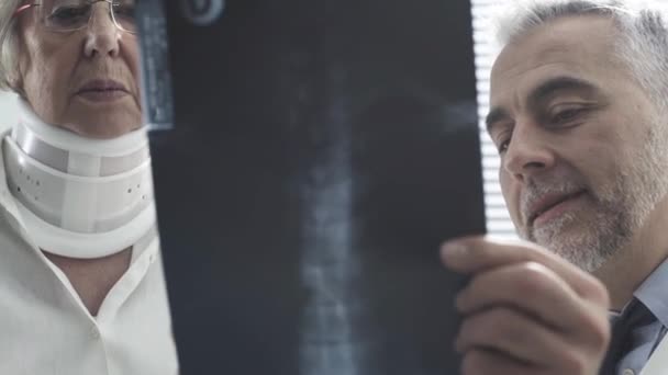 Doctor examining an injured senior woman with cervical collar — Stock Video