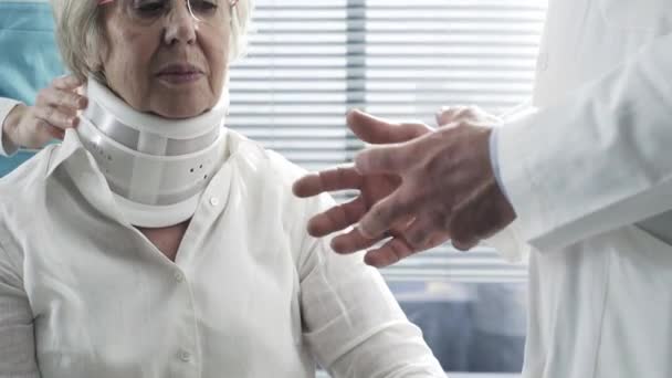 Medico che esamina una donna anziana ferita con collare cervicale — Video Stock