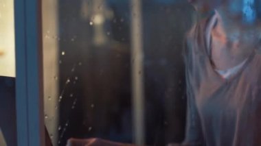 Pencerenin yanındaki bilgisayara bağlanan genç bir kadın.