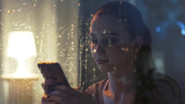 Sorrindo menina mensagens de texto com seu telefone à noite — Vídeo de Stock