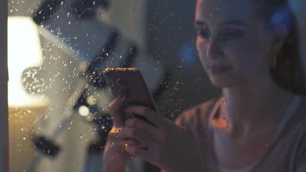 Улыбающаяся девушка переписывается с телефоном по ночам — стоковое видео