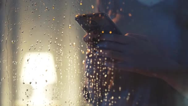 Woman connecting with her phone next to a window — Stock Video